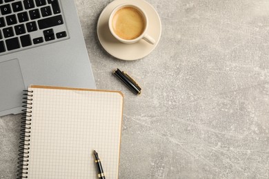 Photo of Notebook, pen, laptop and cup of coffee on light gray table, flat lay. Space for text