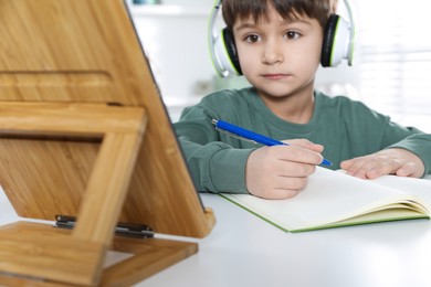 Photo of Cute little boy with tablet studying online at home, focus on hand. E-learning