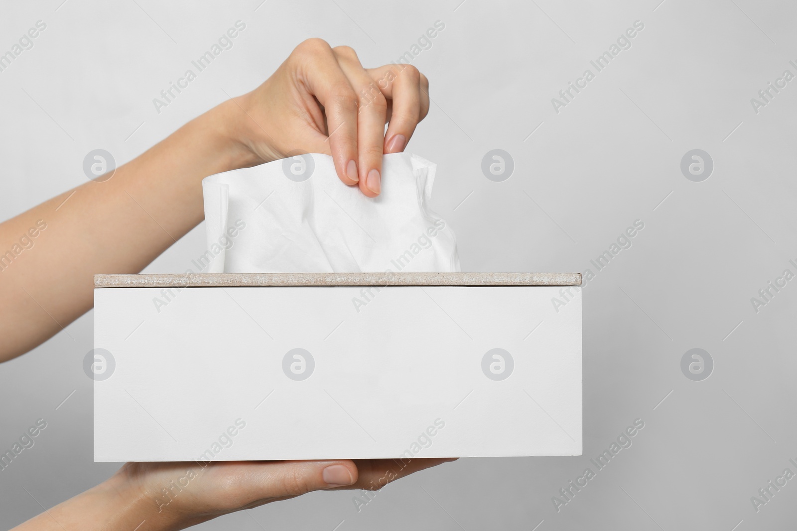 Photo of Woman taking paper tissue from holder on light background, closeup