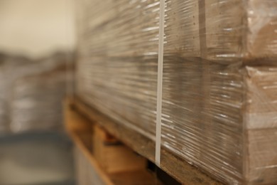 Photo of Stacks of merchandise wrapped in stretch film on wooden pallet, closeup