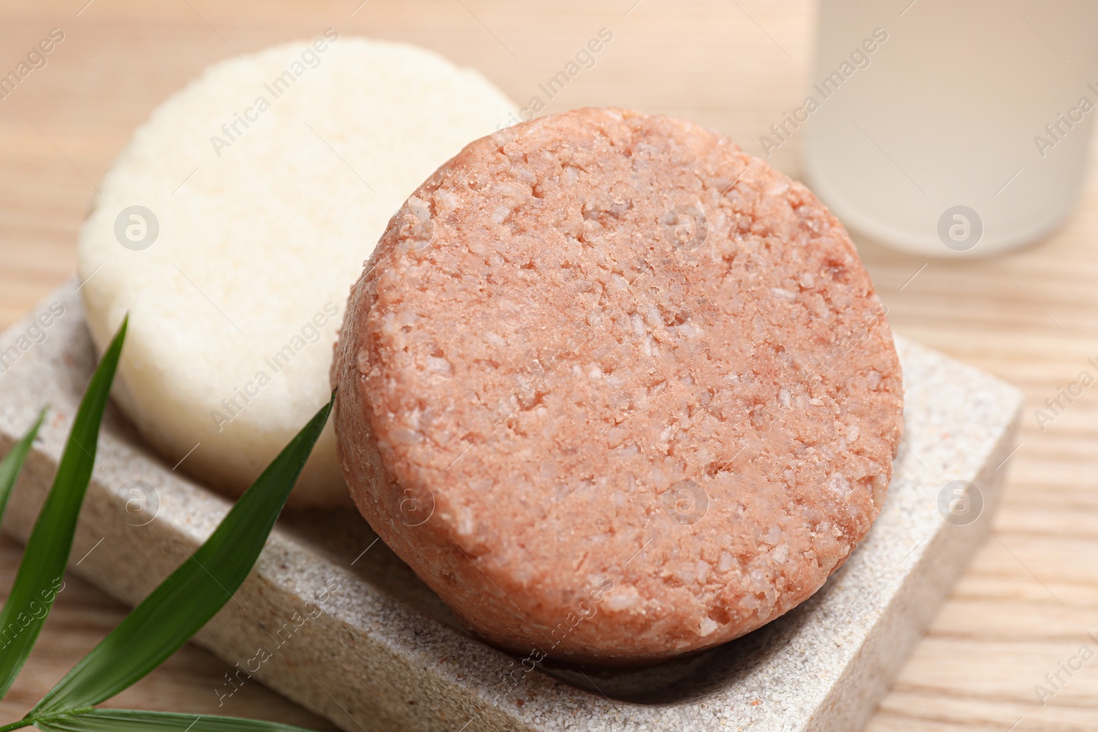 Photo of Dish with solid shampoo bars on wooden table, closeup