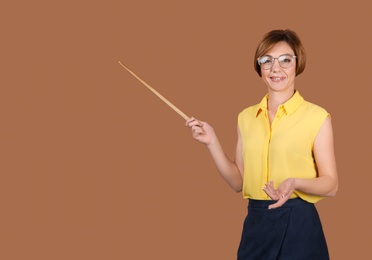 Portrait of female teacher with pointer on color background