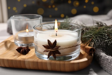 Photo of Decorated scented candles in glass holders on wooden tray