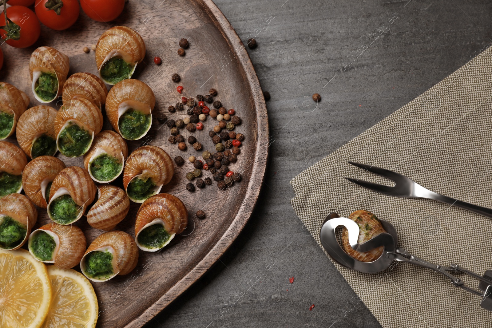 Photo of Delicious cooked snails served on grey table, flat lay