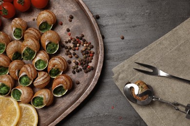 Delicious cooked snails served on grey table, flat lay