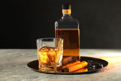 Tray with whiskey, cigars and cutter on grey table