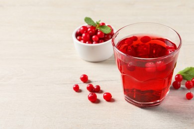 Photo of Tasty refreshing cranberry juice, mint and fresh berries on light wooden table. Space for text