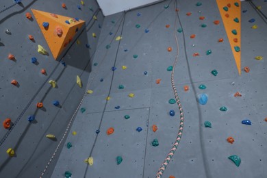 Photo of Climbing wall with holds and ropes in gym, low angle view. Extreme sport