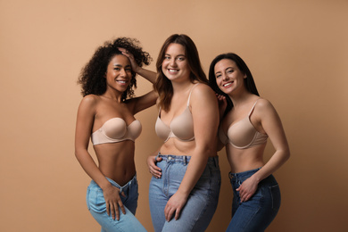 Photo of Group of women with different body types in jeans and underwear on beige background