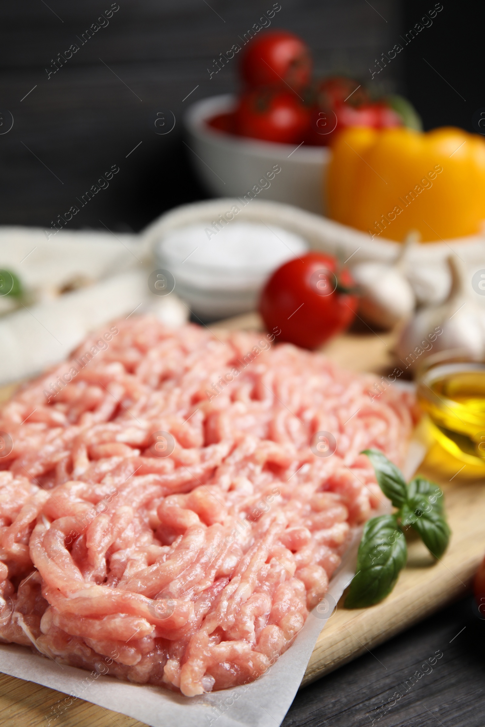 Photo of Raw chicken minced meat with basil on black wooden table, closeup