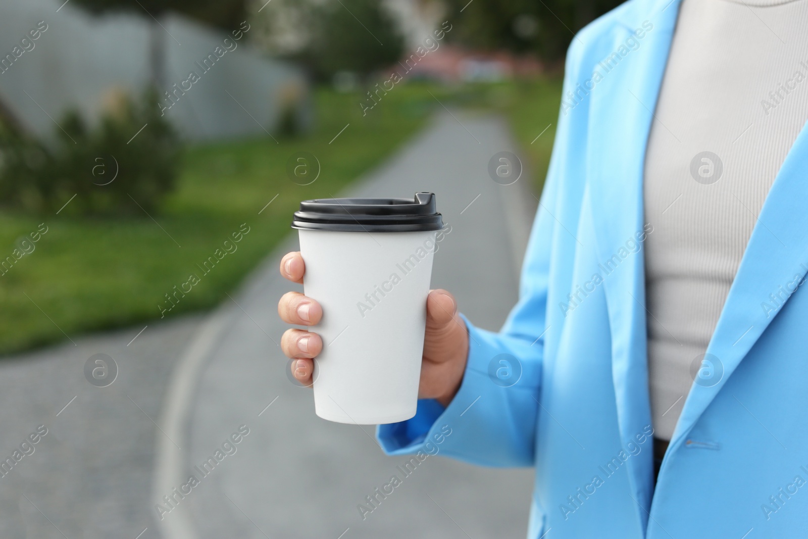 Photo of Coffee to go. Woman with paper cup of drink outdoors, closeup