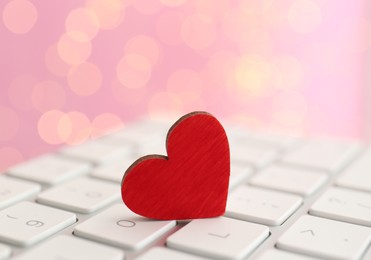 Photo of Red wooden heart on computer keyboard, closeup. Online dating