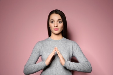 Photo of Woman showing HOUSE gesture in sign language on color background