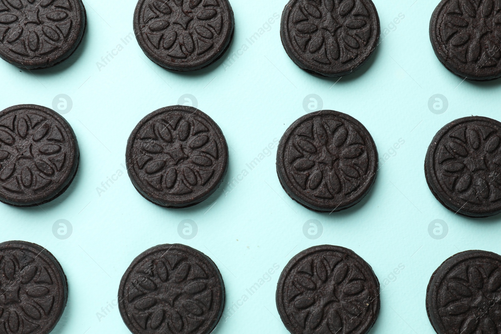 Photo of Tasty sweet sandwich cookies on light blue background, flat lay