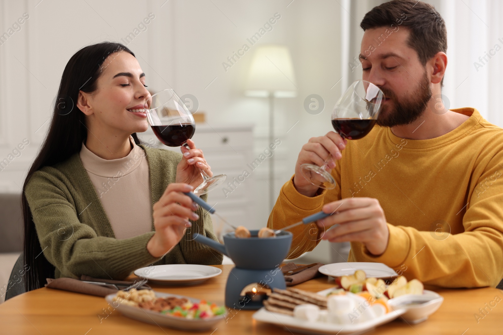 Photo of Affectionate couple enjoying chocolate fondue during romantic date at home