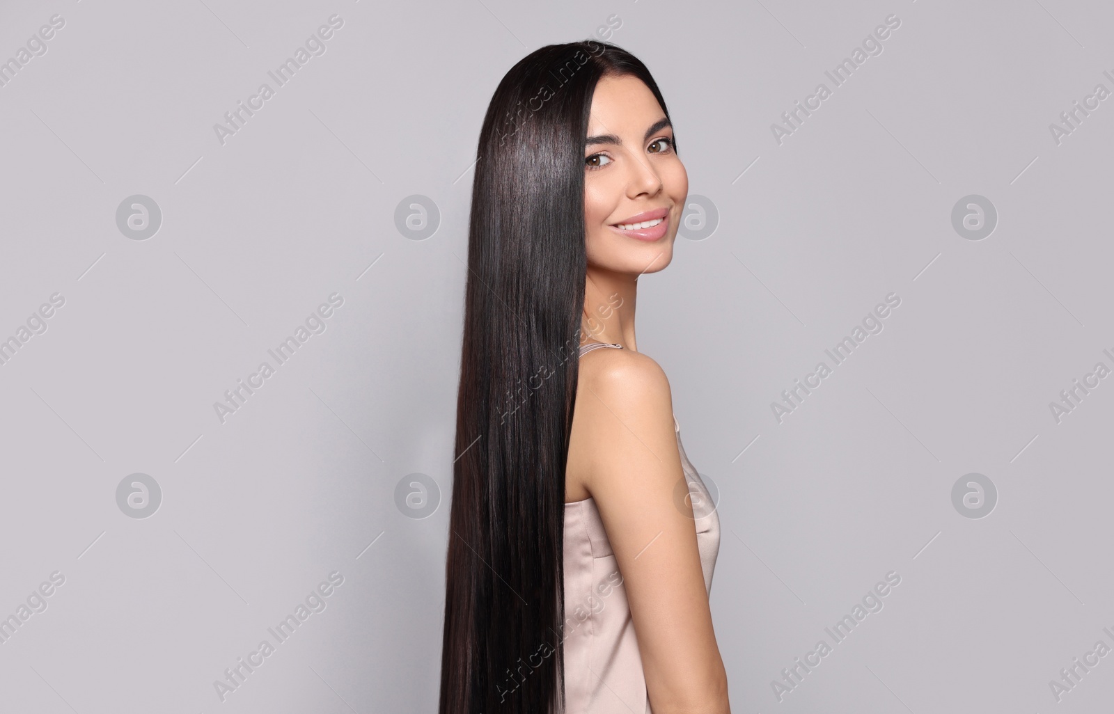 Photo of Portrait of beautiful young woman with healthy strong hair on light grey background