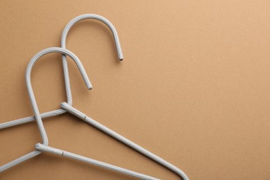 Empty hangers on brown background, top view. Space for text