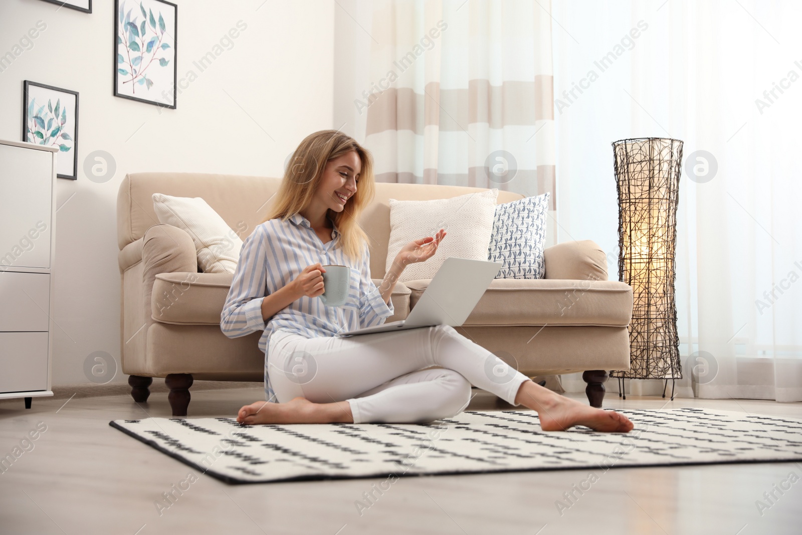 Photo of Pretty young woman with laptop sitting on floor at home