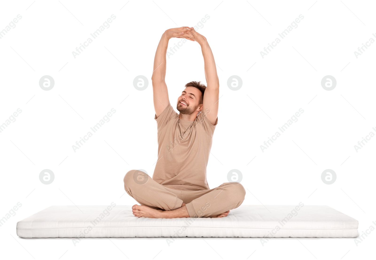 Photo of Man stretching on soft mattress against white background