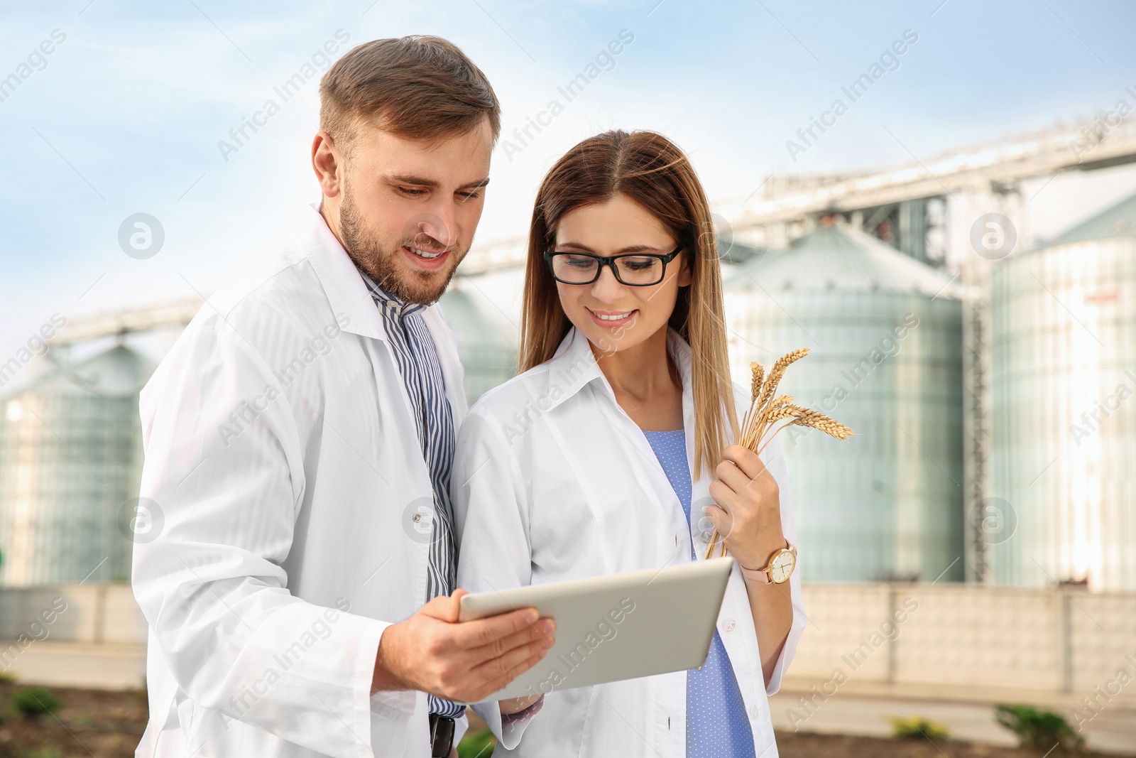 Photo of Young agronomists near modern granaries. Cereal farming