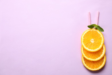 Photo of Creative image of summer cocktail made with orange slices, mint and straw on lilac background, top view. Space for text