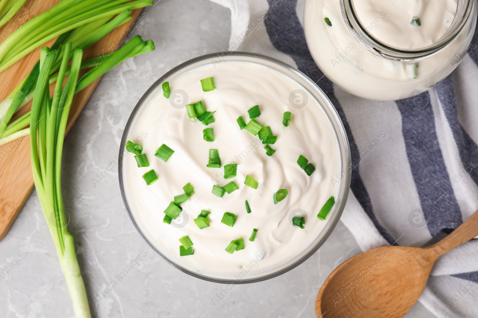 Photo of Fresh sour cream with onion on grey marble table, flat lay