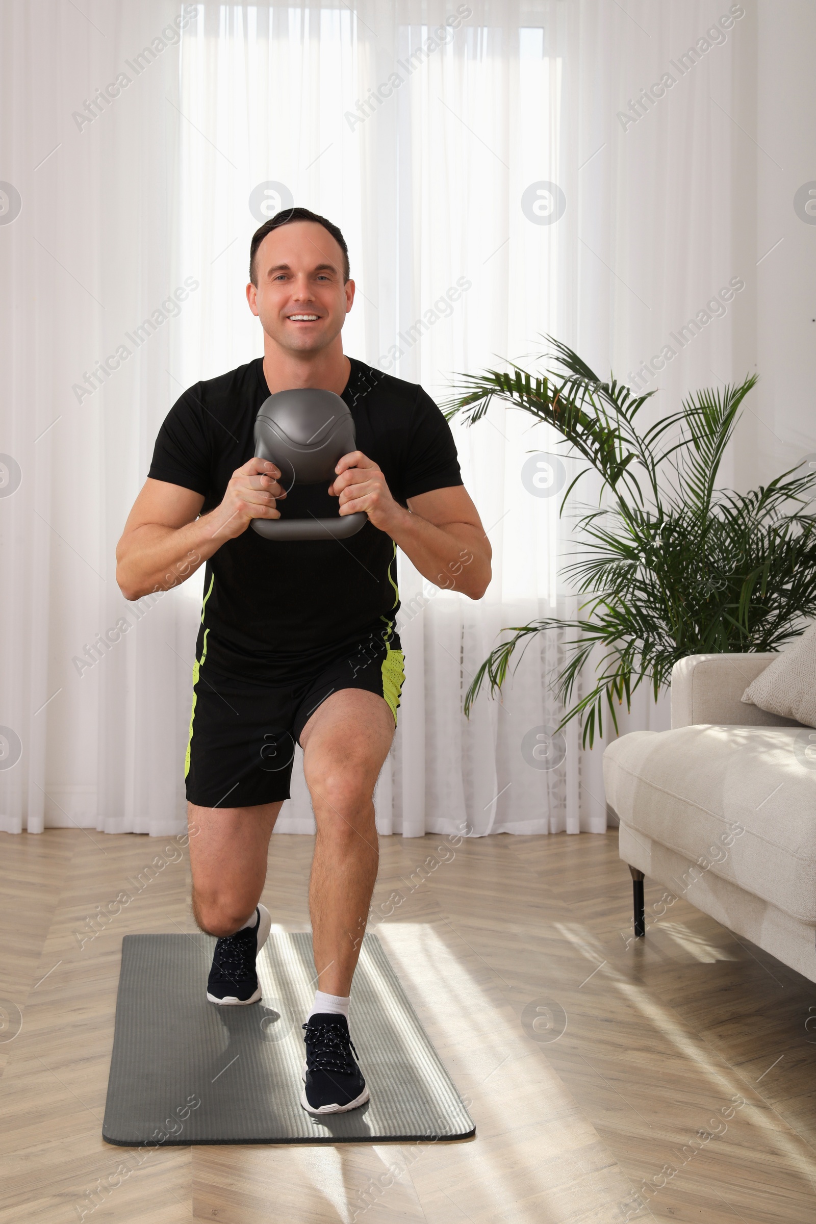 Photo of Muscular man training with kettlebell at home