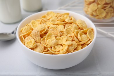 Photo of Tasty crispy corn flakes in bowl on white table, closeup. Breakfast cereal