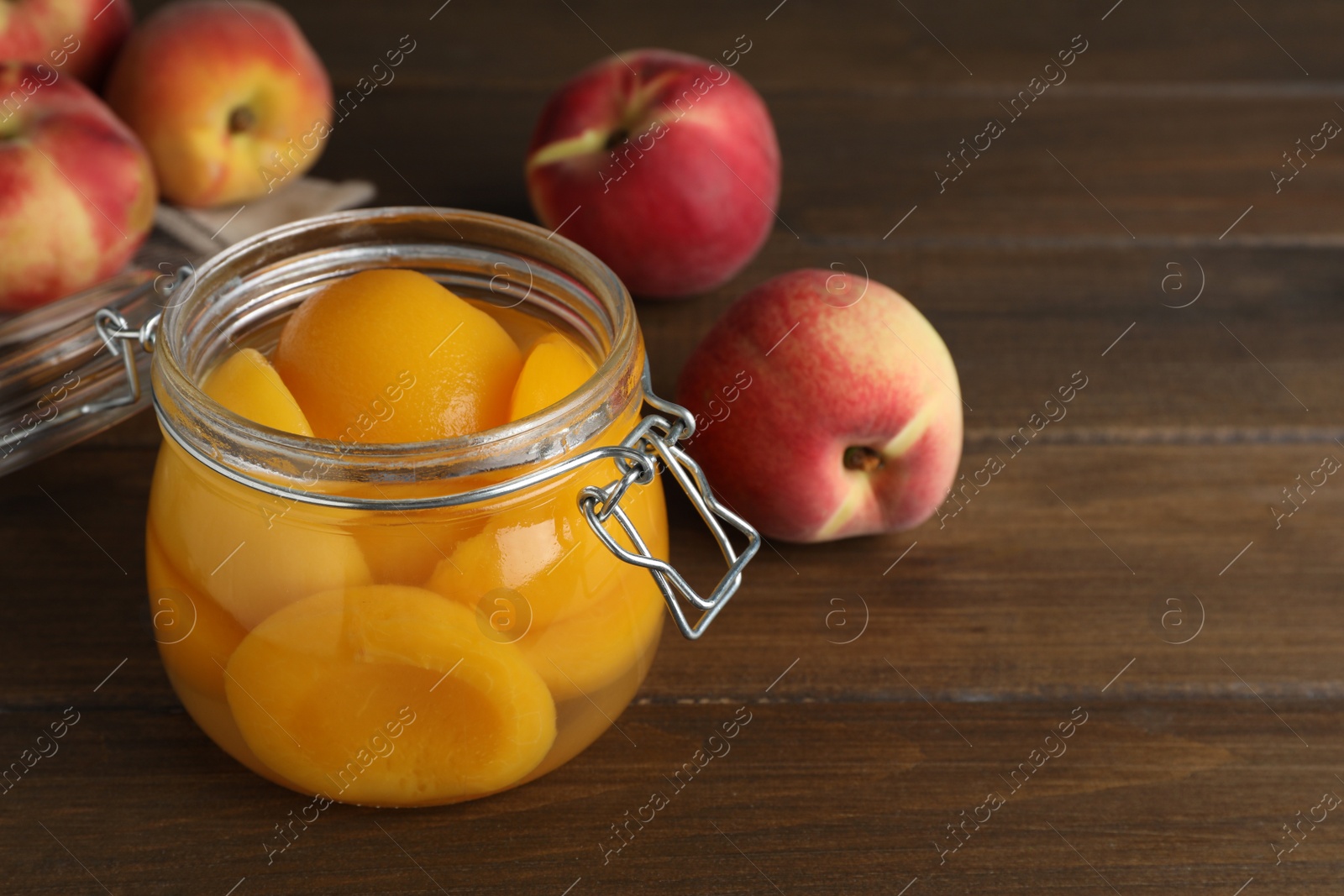 Photo of Canned peach halves in glass jar on wooden table, space for text