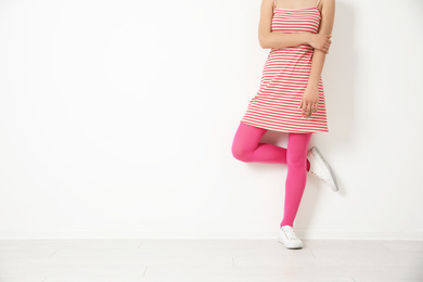 Woman wearing pink tights near white wall, closeup. Space for text