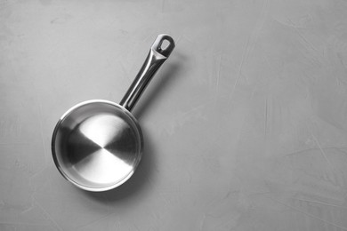 Empty steel saucepan on light grey textured table, top view. Space for text