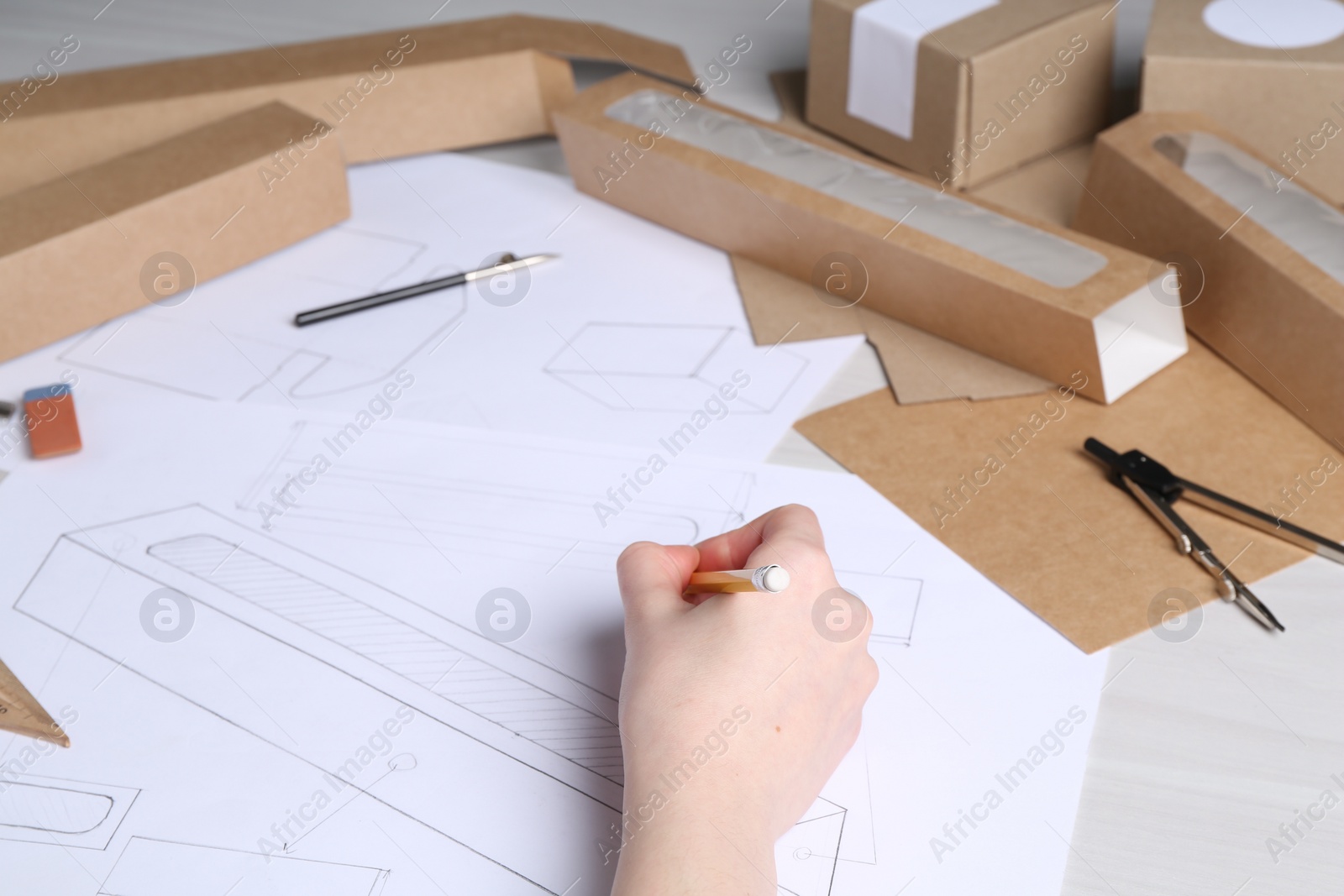 Photo of Woman creating packaging design at light wooden table, closeup