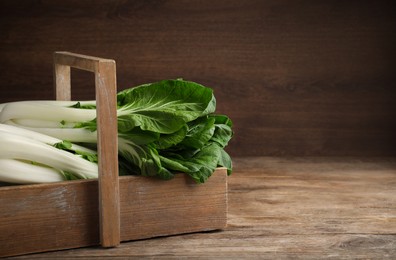 Photo of Fresh green pak choy cabbages in crate on wooden table. Space for text