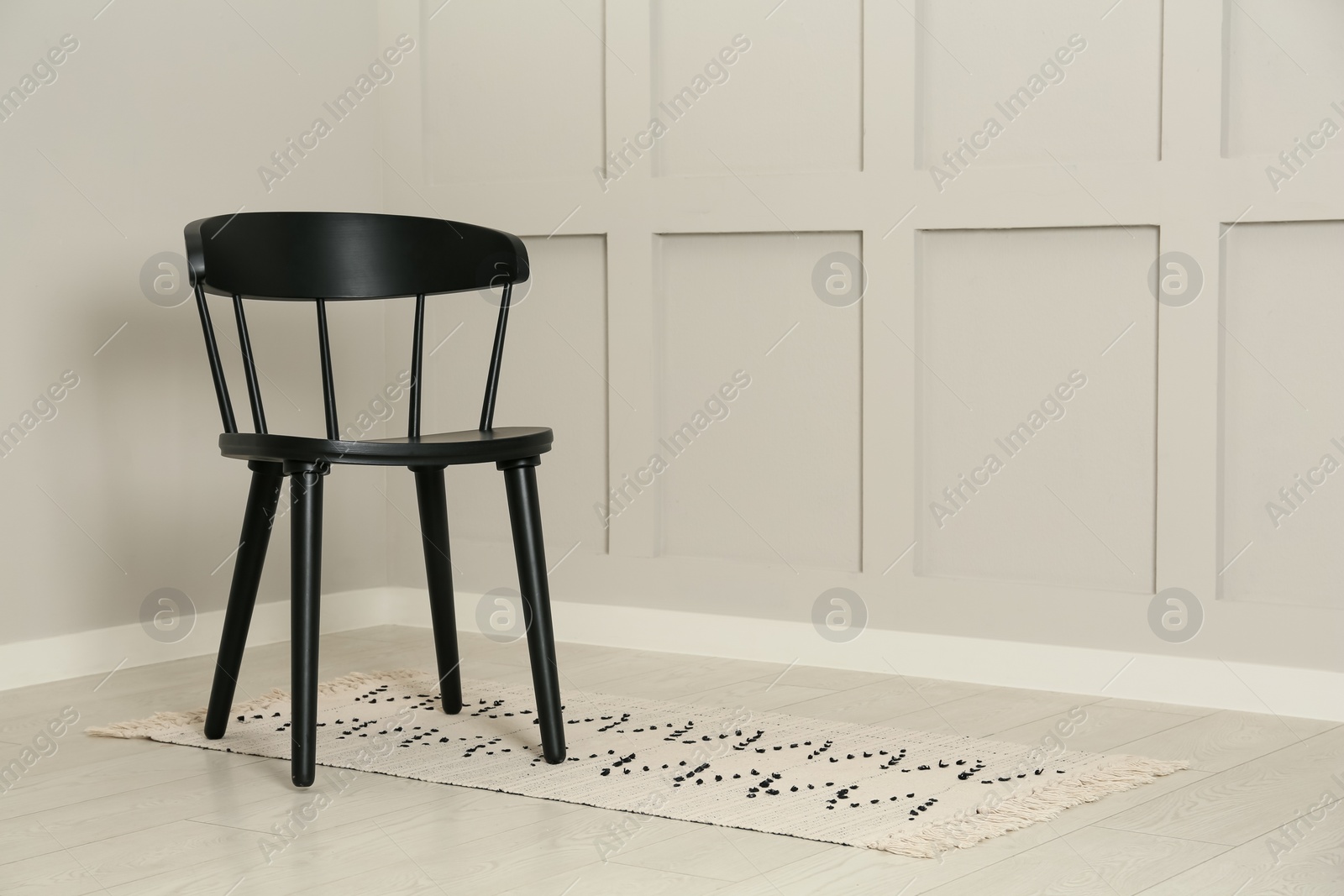 Photo of Black wooden chair near light wall in room. Space for text