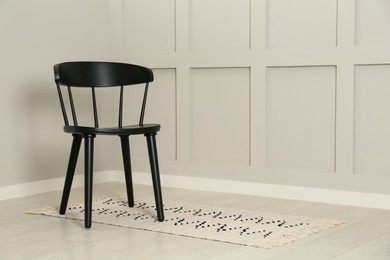 Photo of Black wooden chair near light wall in room. Space for text