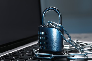 Photo of Cyber security. Metal combination padlock with chain on laptop, closeup