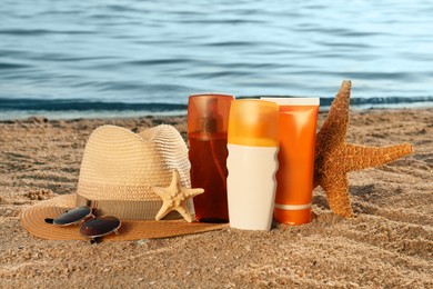 Photo of Sun protection products and beach accessories on sand near sea