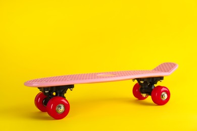 Pink skateboard on yellow background. Sport equipment