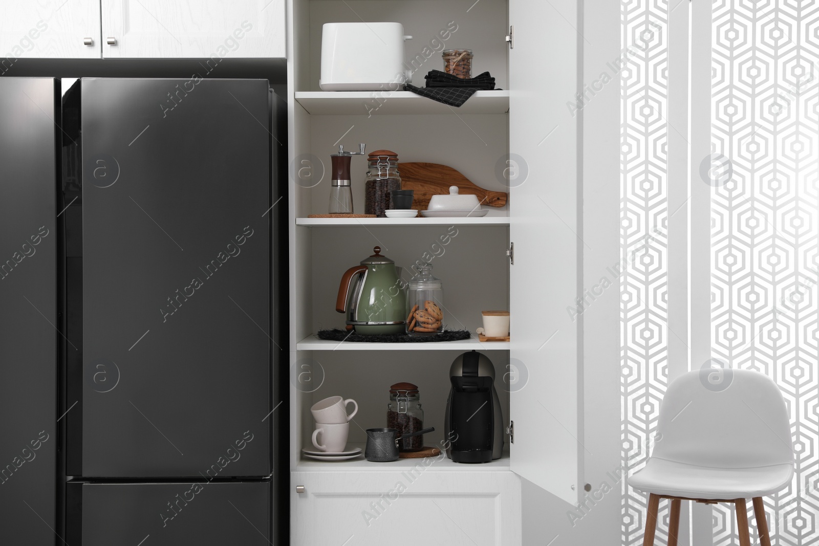 Photo of Manual coffee grinder and other appliances on shelving unit in kitchen