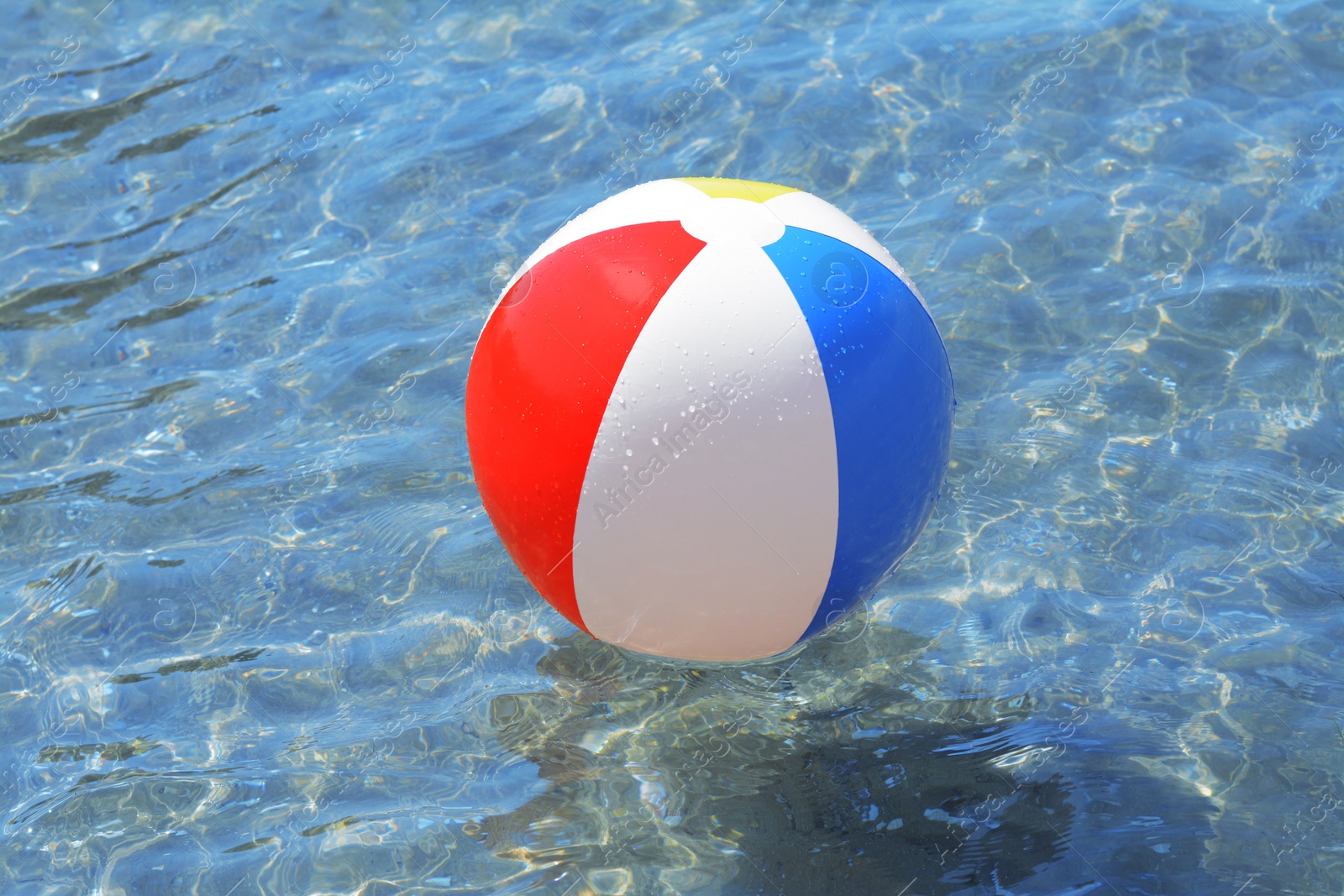 Photo of Colorful beach ball floating in sea on sunny day
