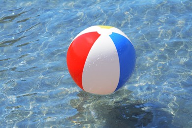 Colorful beach ball floating in sea on sunny day