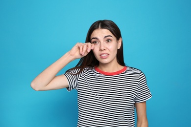 Photo of Young woman rubbing eye on color background. Annoying itch