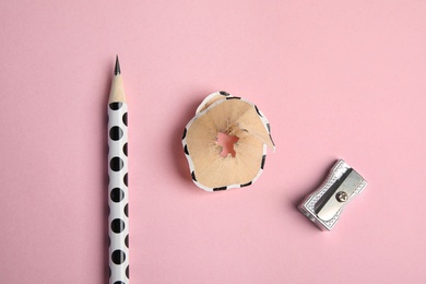 Pencil, sharpener and shaving on pink background, flat lay