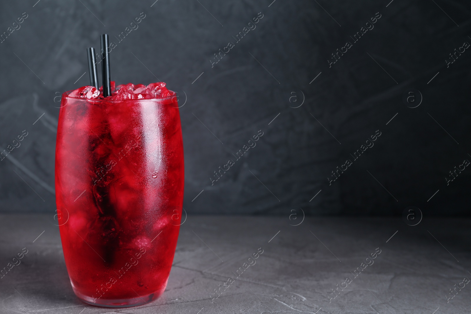 Photo of Bright cocktail with ice cubes on light grey table, closeup. Space for text