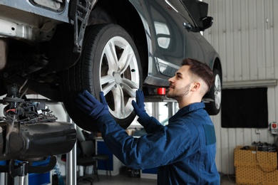 Photo of Technician checking car on hydraulic lift at automobile repair shop