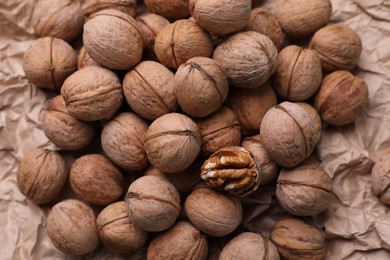 Photo of Tasty walnuts on crumpled paper, top view