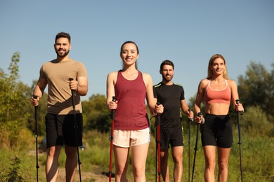 Photo of Group of happy people practicing Nordic walking with poles outdoors on sunny day