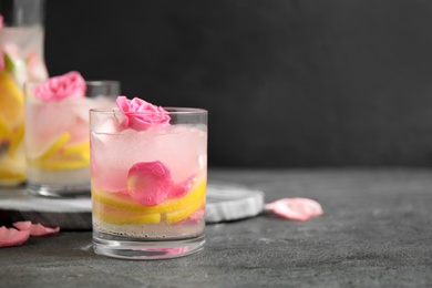 Delicious refreshing drink with lemon and roses on grey table. Space for text