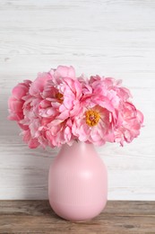 Photo of Beautiful bouquet of pink peonies in vase on wooden table