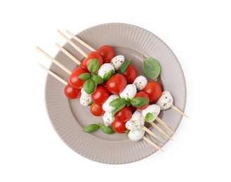 Photo of Plate of skewers with tomatoes, mozzarella balls, basil and spices isolated on white, top view